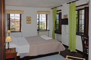 1 dormitorio con 1 cama con cortinas verdes y TV en Archontiko Parisis, en Lavkos