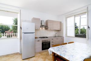 eine Küche mit einem weißen Kühlschrank und einem Tisch in der Unterkunft Casa con veranda in Posada