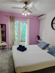 um quarto com uma grande cama branca com paredes roxas em Lindsey Hôtel em Saint-Pierre