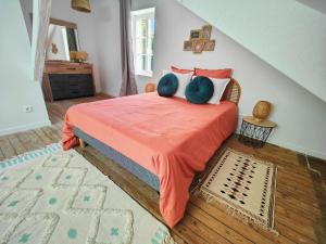 a bedroom with a bed with an orange blanket at La maison du bien-être in Le Bois-Robert