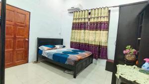 een kleine slaapkamer met een bed en een deur bij Raniah Homestay2 in Kuching
