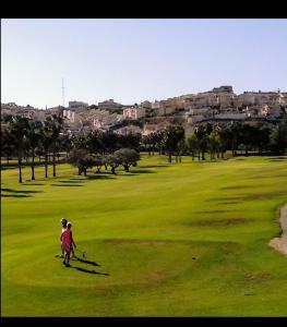 a woman walking a dog on a golf course at Golf house Marquesa in Rojales