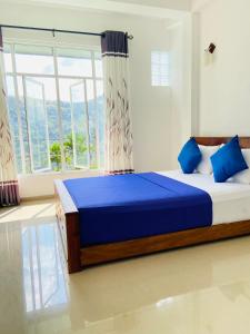 a bedroom with a bed with blue sheets and a window at Springvalley Holiday Home in Badulla