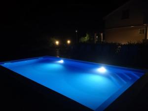 una piscina illuminata di notte con luci blu di Lavanda Apartments&Studios a Pinezići
