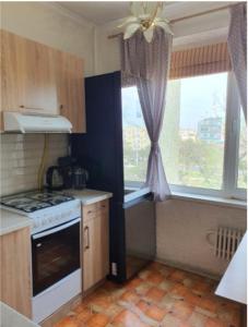 a kitchen with a stove top oven next to a window at Уютная квартира в центре города. in Aktau