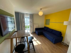 a living room with a blue couch and a tv at Buntes Wohnen in Düren in Düren - Eifel