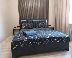 a bedroom with a large black bed with a blue blanket at Астана 18/1 in Ustʼ-Kamenogorsk