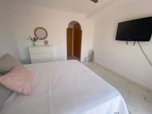 een witte slaapkamer met een bed en een flatscreen-tv bij Horia Seaside in La Herradura