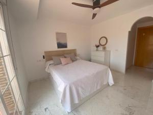 een witte slaapkamer met een bed en een plafondventilator bij Horia Seaside in La Herradura