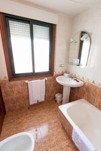a bathroom with a tub and a sink and a mirror at Hostal O Camouco in Portonovo