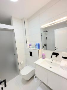 a white bathroom with a toilet and a sink at Suite In White in ‘Akko