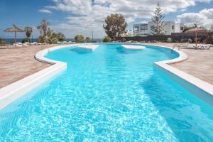 a large swimming pool with blue water at Lanzahost Tuscan Atlantico in Costa Teguise