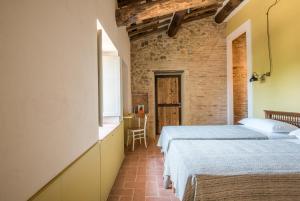 - une chambre avec 2 lits et un mur en briques dans l'établissement Agriturismo Casalino18, à Tognazza