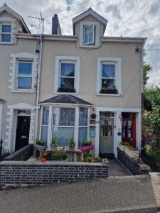 Casa blanca con puerta roja y ventanas en Town Cottage ground floor appartment en Bridgend