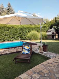 an umbrella and a bench next to a pool at Casa Botisa - Luxury Villa with private pool in Kumanovo