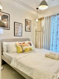 Una cama con sábanas blancas y almohadas en un dormitorio en Scandinavian 1 BR beside SM CDO w POOL and Netflix, en Cagayan de Oro