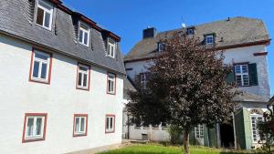 um edifício branco com acentos vermelhos ao lado de uma árvore em Kloster Steinfeld Gästehaus em Kall
