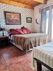 a bedroom with two beds and a brick wall at Die Plasie on-suite rooms in Hartbeespoort