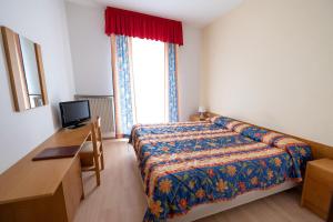 Schlafzimmer mit einem Bett, einem Schreibtisch und einem Fenster in der Unterkunft Hotel Posta in Comano Terme