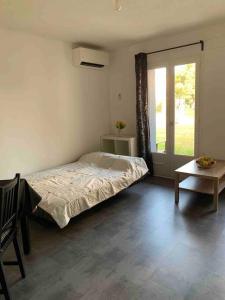 a bedroom with a bed and a table and a window at Appartement Cosy Tout Confort PARKING AC WIFI LINEN INCLUDED pool access extra in Canet-en-Roussillon