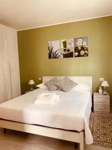 a bedroom with a large white bed with green walls at Corte 22 B&b e Appartamenti in Borgomanero