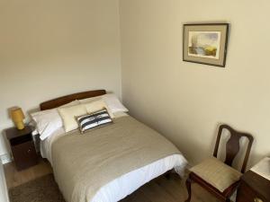 a small bedroom with a bed and a chair at Flaherty Cottage, Ballyconneely in Ballyconneely
