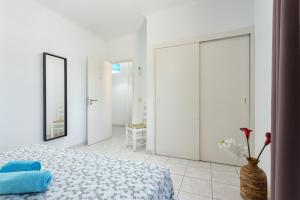 ein weißes Schlafzimmer mit einem Bett und einer Vase mit Blumen in der Unterkunft Fresh Sunny Flat with Pool & Terrace by Host Wise in Olhos de Água