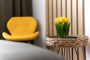 un jarrón de flores amarillas sobre una mesa con una silla amarilla en Emerald Apartment en Baia Mare