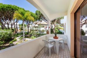 einen Balkon mit einem Tisch, Stühlen und Bäumen in der Unterkunft Fresh Sunny Flat with Pool & Terrace by Host Wise in Olhos de Água