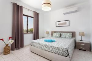ein weißes Schlafzimmer mit einem Bett und einem Fenster in der Unterkunft Fresh Sunny Flat with Pool & Terrace by Host Wise in Olhos de Água