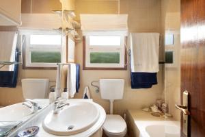 baño con lavabo, aseo y ventanas en Casa da Ria 78, en Torreira