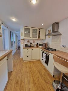 cocina con armarios blancos y suelo de madera en Town Cottage ground floor appartment en Bridgend