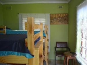 a bedroom with a bunk bed and a chair at Mkhumbane Backpackers in Durban