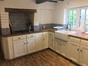 a kitchen with white cabinets and a sink at Cherry Tree Cottage Close to Belvoir Castle. Sleeps 6. Dogs v welcome. in Redmile
