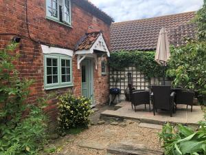 a brick house with a table and an umbrella at Cherry Tree Cottage Close to Belvoir Castle. Sleeps 6. Dogs v welcome. in Redmile