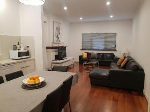 ein Wohnzimmer mit einem schwarzen Sofa und einem Tisch in der Unterkunft Leisurely Manor - spacious three bedroom home in Fremantle in Fremantle