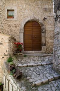 a wooden door in a stone building with flowers at Le Siepi Country House in Santo Stefano di Sessanio