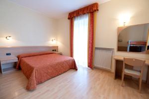 Schlafzimmer mit einem Bett, einem Schreibtisch und einem Fenster in der Unterkunft Hotel Posta in Comano Terme