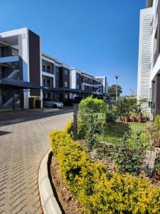 a row of buildings with yellow flowers next to a street at SaronaC102 in Gaborone