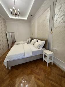 a bedroom with a large white bed and a table at Apartments & Room - Korzo in Sombor