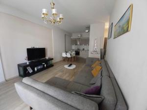 a living room with a gray couch and a dining room at Sol's M2 White Modern Apartments in Tbilisi City