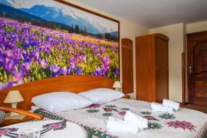 un dormitorio con una pintura de una cama con flores en Willa Kubik, en Zakopane