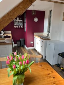 Studio Apartment في ويلْزْ: مطبخ مع طاولة مع إناء من الزهور الزهرية