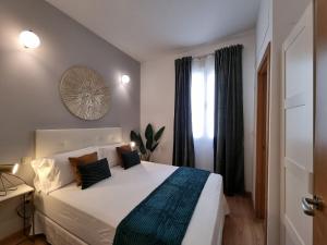 Un dormitorio con una gran cama blanca y una ventana en Apartamentos San Isidro, en Madrid