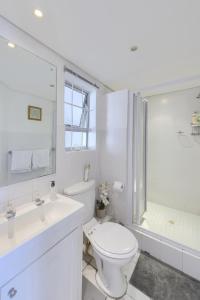 a white bathroom with a toilet and a shower at Loft Apartment off Kloof with Table Mountain views in Cape Town