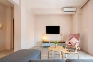 a living room with a couch and a table and a tv at Phaedrus Living Athens City Center Geraniou in Athens