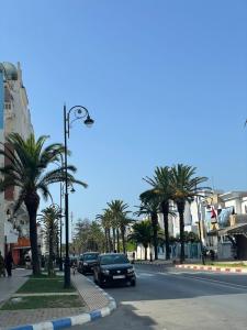 a car is driving down a street with palm trees at Appartandalus in Larache