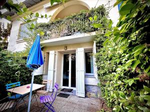 a house with a table and a blue umbrella at Villa Etoile Cannes in Cannes