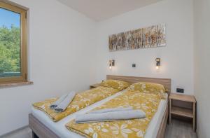 a bedroom with a bed with yellow sheets and a window at Apartment Moderna Soline in Dobrinj