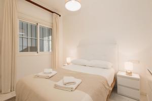 una camera da letto bianca con un letto e asciugamani di 3 bedroom apartment with incredible sea views in Manilva a Manilva